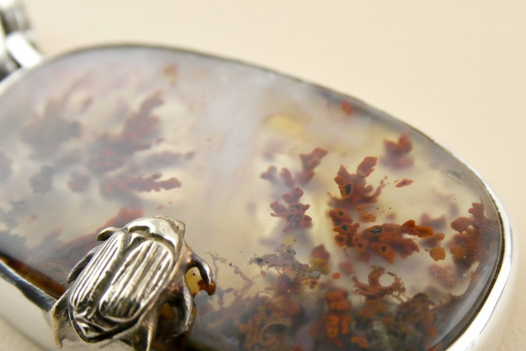 Jewelry with a stone and gold beetle charm on a white background